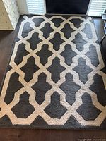 Full top view of rectangular 5x7.5 feet rug with gray base and beige geometric pattern under natural light showing overall condition and pattern