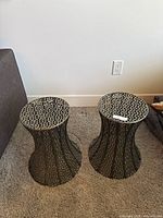 Pair of metal accent tables side by side on carpeted floor, showing top view and geometric openwork detailing.