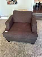 Front view of brown fabric armchair showing seat cushion and straight armrests, minimal wear