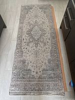 Full top view of the runner rug showing overall pattern and condition, with orange non-slip mat visible on one side.