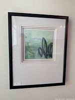 Front view of the framed artwork showing the abstract design with green and black colors inside a black frame.