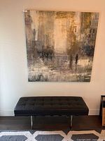 Front view of large square abstract artwork hanging on a wall above a black bench.