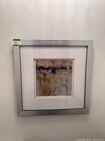 Frontal view of the framed abstract artwork by Karen Parker featuring layered warm tones and geometric textures, framed in a silver metal frame with white matting.