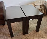 Two brown solid wood end tables standing on carpet side by side