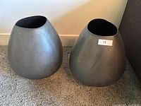 Photo showing front view of two grey ceramic pots with oval openings and minor chips on rim. One pot has a label '13'.