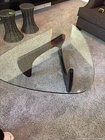 Full view of triangular glass top and three-legged base on carpet