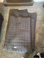 Folded large brown quilt showing square stitched pattern and thick texture