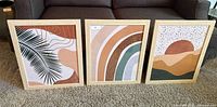 Three modern abstract wooden framed prints displayed together, showing different color combinations and designs