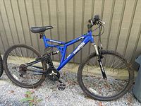 Side view of the blue Mongoose Dynamic mountain bike showing full frame, tires, saddle, pedals, and suspension.