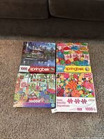 Four puzzles displayed on carpet floor, including three Springbok puzzles and one Plant Paradise puzzle