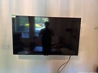 Front view of Samsung 50 inch LED TV mounted on wall with power cord hanging.