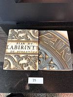 Two Sid Dickens decorative tiles side by side on a black surface with a small '35' label beneath them.