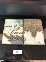 Photo of two Sid Dickens memory tiles side by side, showing vintage postcard script and embossed lace design.