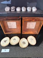 Two wooden picture frames and four real wood coasters arranged on a black surface with small numbered paper