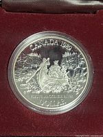 1989 Canadian silver dollar coin showing a canoe with three people, detailed river rocks and trees, and inscriptions 'CANADA 1989' and 'DOLLAR'.