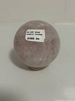 Front view of the rose quartz sphere showing a price sticker of $400 and crystal clarity with natural internal patterns.