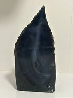Front view of the polished dark agate geode showing intricate natural banding with tapered pointed shape.