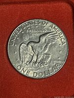 Reverse side of the 1978 Eisenhower dollar coin showing eagle landing on Moon clutching olive branch with inscriptions around edge.