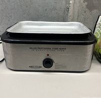 Front view of Deluxe Professional Stone Heater, stainless steel with black trim, control knob, and heating tray on top.