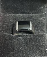 Front view of black onyx gemstone in silver band on black velvet background