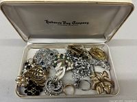 Vintage Hudson Bay Company jewelry box open showing mixed jewelry including brooches, rings, and necklaces inside.
