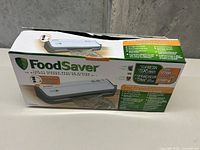Original packaging box for FoodSaver FM2000 vacuum sealing system showing product image and features.