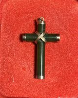 Jade cross pendant with gold accents on a red velvet background.