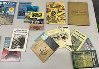 Overview of the lot on a white table showing all the magazines and books spread out, titles visible.