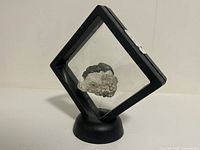 Front view of natural purple phantom fluorite mineral specimen in black display frame on round base