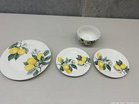Set of four Royal Norfolk lemon floral dinnerware pieces: two large plates, one smaller plate, and one small bowl shown on a table.