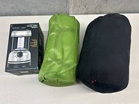Two sleeping bags packed in stuff sacks and boxed Black Series camping lantern arranged on table