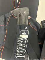 Close-up of the wetsuit collar showing size L1 label and Synergy brand with care instructions.