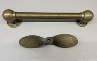 Photo of vintage brass boat handle fitting and two-blade propeller on white background.