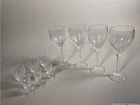 Ten Waterford crystal glasses of varied sizes arranged in a row against a white background