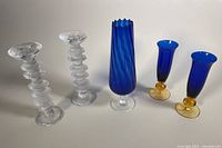 All items together showing pair of clear glass candleholders with ringed design, blue swirl vase, and blue glass flutes