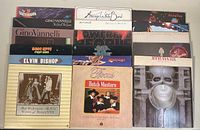 Photo of vinyl record albums stacked including Gino Vannelli, Rick Wakeman, Average White Band, Elvin Bishop among others