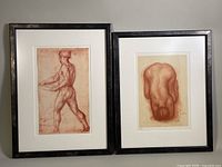 Two framed sanguine sketch prints on paper, depicting male nudes with dark wood frames and white matting, shown side by side.