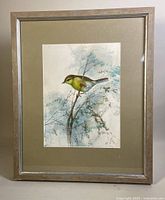 Framed watercolour painting with bird and branch, silver frame with green mat visible, frame has chips