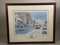 Framed print showing snowy street scene with streetcar, cars and buildings on Queen St. West