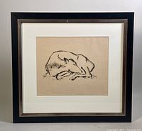 Full view of the framed artwork showing the black frame, white mat, and the signed drawing of a reclining animal on beige paper.