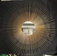 Full view of the round starburst wall mirror with brass rods radiating out from a central circular mirror.
