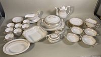 Full set of Spode Queen's Gate bone china items arranged on a surface showing the platter, serving bowls, coffee pot, creamer, sugar bowl, gravy boat, soup bowls, teacups and saucers.