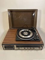 Vintage Holiday stereo system with woodgrain finish showing record player turntable with dust cover open.