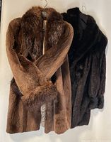 Both brown muskrat and black mink coats hanging side by side