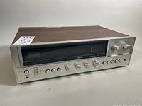 Front 3/4 view showing wood veneer top and brushed aluminum front panel with control knobs and display.