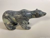 Side view of vintage soapstone polar bear sculpture showing shape, natural stone pattern, and minor scuffs.