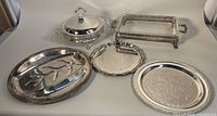 Five pieces of vintage silver plated servingware including warming casserole with lid, rectangular tray, two round trays, and meat tray