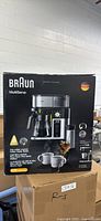 Front view of the boxed Braun MultiServe KF9050 coffee maker showing product image and branding.