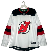 Front view of the jersey showing New Jersey Devils logo, red and black stripes on sleeves, black shoulder panels, and red collar.