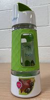 Green Fruition 20oz fruit infuser water bottle with textured grip, clear middle, and white and green cap, set against a neutral background.